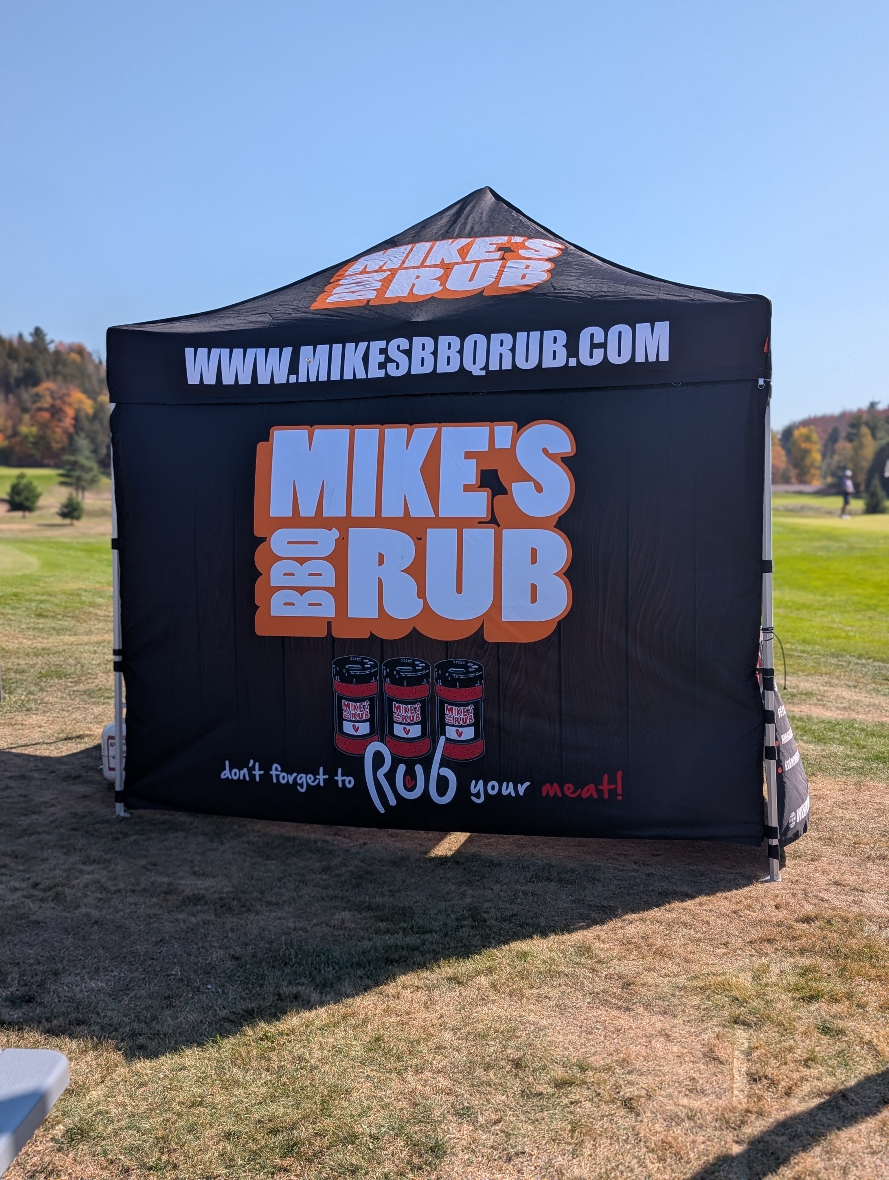 Black pop-up tent with 'Mike's BBQ Rub' branding in an outdoor setting.
